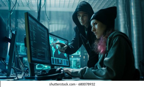 Team of Boy and Girl Hackers Organize Advanced Virus Attack on Corporate Servers. They Work Together. Place is Dark and Has Multiple displays.