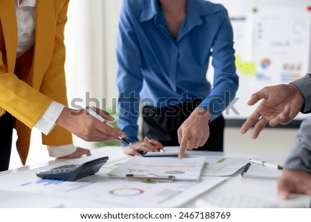 Team brainstorming session with documents and graphs on the table, focusing on business strategy and collaboration in a modern office environment.