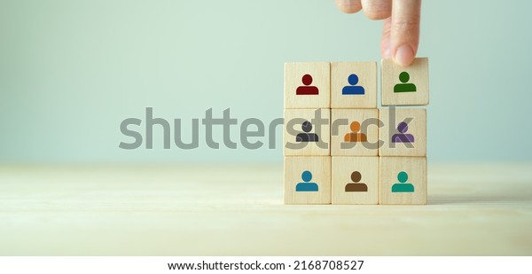 Team building and diversity concept. Work\
collaboration for achieving goal and successful business.\
Productive people skills. Hand placed wooden cubes with team\
diversity building icons. HRM\
Banner.