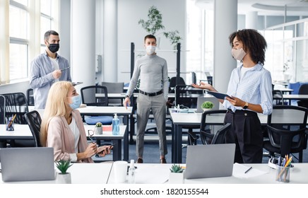 Team Building And Teamwork During Meeting. African American Woman Manager With Tablet In Hand Gives Tasks To Workers In Protective Mask Keeping Social Distance In Interior Of Modern Office, Panorama