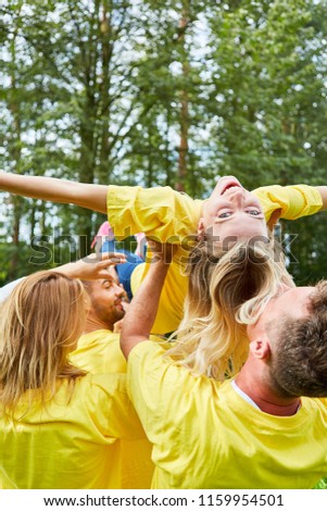 Team in the team building workshop trains confidence and makes woman float