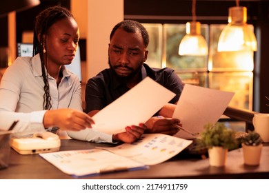 Team of business partners brainstorming ideas to plan report, doing project research with data on documents. Analyzing paperwork to create presentation during sunset in office with big windows. - Shutterstock ID 2174911759