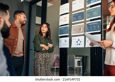 Team of businesspeople analyzing some reports in a boardroom. Group of multicultural businesspeople having a meeting in a modern office. Diverse entrepreneurs collaborating on a project.