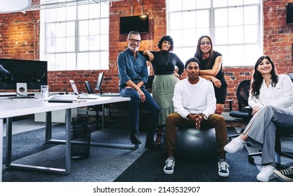 Team of businesspeople smiling at the camera in a creative office. Business colleagues grouped together in a modern workplace. Diverse team of businesspeople looking cheerful. - Shutterstock ID 2143532907