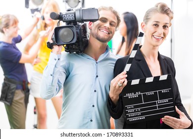 Team or Cameraman with camera and woman with take clap or board on Film Set 