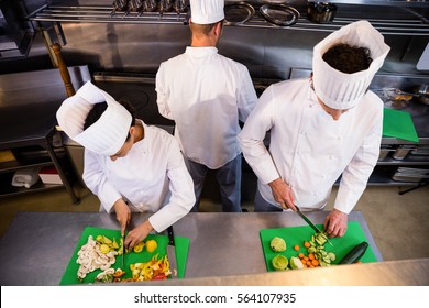 Team of chefs chopping vegetables on the chopping board in the kitchen - Powered by Shutterstock