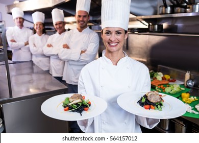 Team of chefs in the kitchen with one presenting dishes
