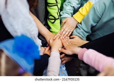 Team of children put hands together and unite to win game in playground. Summer holidays in camp, tourist center. Walking and playing outdoors, sport activity and healthy lifestyle, recreation.  - Powered by Shutterstock