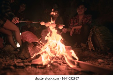 Team of climbers man and woman hiker camping.They are sitting around fire camp in the cave. Hiking, hikers, team, mountain, cave, activity concept.