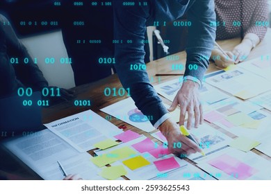 Team collaborating with sticky notes and documents on a table, overlaid with binary code, symbolizing teamwork, planning, and digital innovation. Business and technology image.