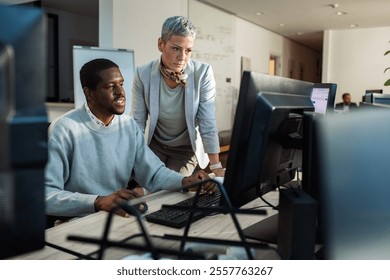 Team collaboration at office desk with dual monitors and brainstorming