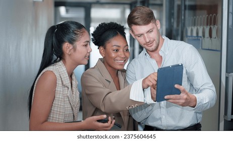 Team of colleagues using a digital tablet together at work. Group of diverse partners discussing project on tablet in office. Business teamwork concept