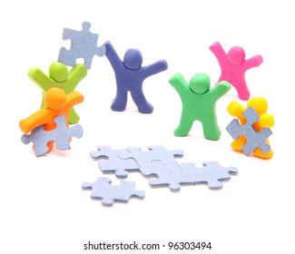 team of colorful plasticine people solving the puzzle together - teamwork concept - isolated on white - Powered by Shutterstock