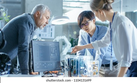 Team Of Computer Engineers Choose Printed Circuit Boards To Work With, Computer Shows Programming In Progress. In The Background Technologically Advanced Scientific Research Center.