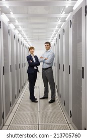 Team Of Computer Technicians Smiling At Camera In Large Data Center