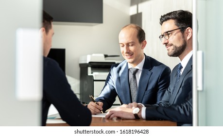 Team of confident successful business people reviewing and signing a contract to seal the deal at business meeting in modern corporate office. Business and entrepreneurship concept.