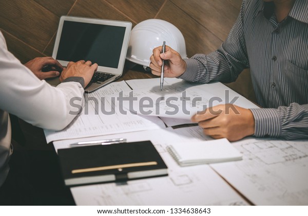 Team of construction engineering or architect\
partner discuss a blueprint while checking information on drawing\
and sketching meeting for architectural project with engineering\
equipment tool.