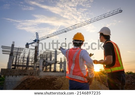A team of construction engineers talks to managers and construction workers at the construction site. Quality inspection, work plan, home and industrial building design project