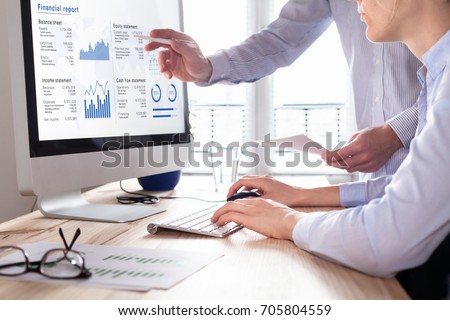 Team of consulting auditors auditing the financial report data of the company (balance sheet, income statement) on computer screen with business charts, fintech