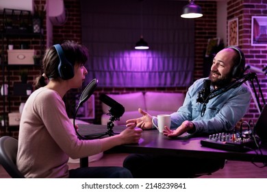 Team of content creators meeting to chat and record podcast episode together, having fun with sound production. Man and woman livestreaming talk show with professional equipment.