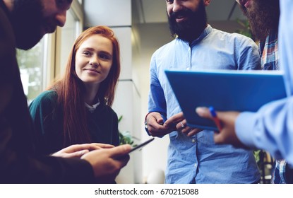 Team of creative IT professionals testing new application for smartphones created developed by young programmers using digital devices and fast wireless connection to internet in coworking office