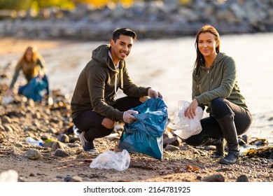 Team Of Dedicated And Smiling Volunteers Collecting Plastic Garbage At Beach