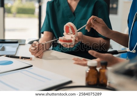 Team of dentists writes reports of working with tooth models and analyzing dental treatments.
