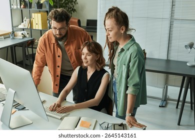 Team at desk using desktop computer while young Caucasian man and young Caucasian woman collaborating on neural network development project