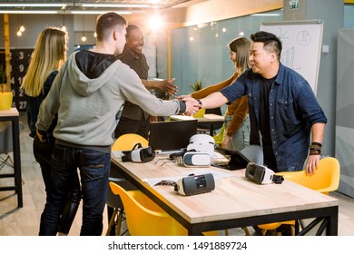 Team of developers working with virtual reality glasses during a business meeting. Young business colleagues brainstorming, hand shaking at the meeting in modern office room
