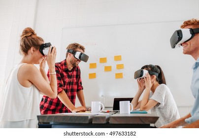 Team Of Developers Working With Virtual Reality Glasses During A Business Meeting. Young Business Colleagues Brainstorming Using VR Goggles.