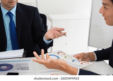 Team Discussion and Data Analysis. Professionals engaged in a collaborative meeting analyzing market data and performance statistics.