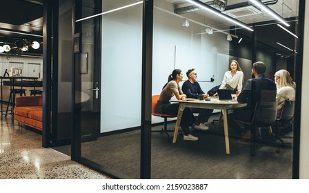 Team of diverse businesspeople having a meeting in a transparent boardroom. Group of business professionals having a discussion during a briefing. Colleagues collaborating on a new project. - Shutterstock ID 2159023887