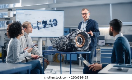 Team Of Diverse Engineers Using Laptop And Tablet To Analyse Electric Vehicle Engine In The Research Laboratory. Modern Industry 4 Sustainable Energy And Emission Reduction Technology.