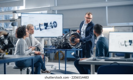 Team Of Diverse Engineers Using Laptop And Tablet To Analyse Electric Vehicle Engine In The Research Laboratory. Modern Industry 4 Sustainable Energy And Emission Reduction Technology Concept.