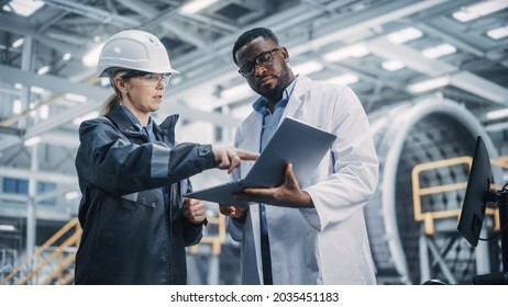 Team Of Diverse Professional Heavy Industry Engineers Wearing Safety Uniform And Hard Hat Working On Laptop Computer. African American Technician And Female Worker Talking On A Meeting In A Factory.