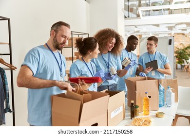 Team of diverse volunteers in protective gloves sorting, packing foodstuff in cardboard boxes, working together on donation project indoors - Shutterstock ID 2117150258