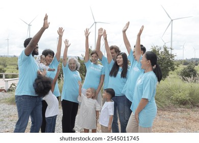 Team of diversity volunteers raising hands before collecting trash at wind turbine farm. Volunteers ready to clean up meadow with garbage collection at turbines park. Ecology and environment - Powered by Shutterstock