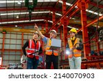 Team of diversity worker inspecting inside the steel manufacturing factory while listening to senior manager advice on using of overhead bridge crane for improving capacity and productivity concept