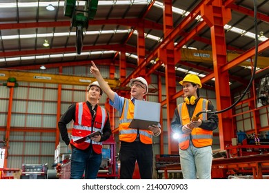 Team of diversity worker inspecting inside the steel manufacturing factory while listening to senior manager advice on using of overhead bridge crane for improving capacity and productivity concept