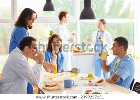 Team of doctors having lunch at table in hospital kitchen
