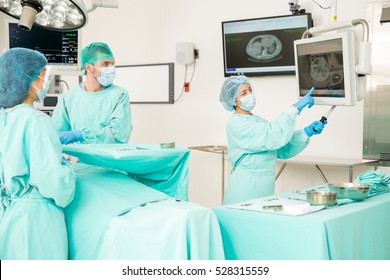 Team of doctors looking at some x-rays during a surgery in an operating room - Powered by Shutterstock