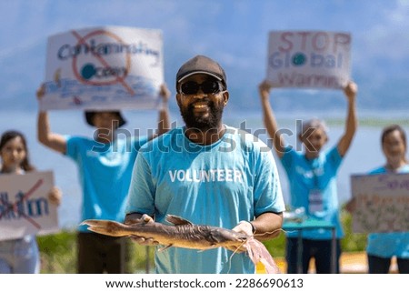 Team of ecologist volunteers are demonstrating rally at ocean for climate change and saving nature with protest sign against pollution and sea contamination for wildlife and biodiversity