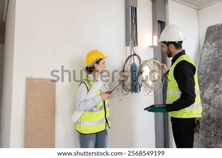 team electrical engineers or technicians is professionally inspecting the wiring and systems in the building. Check electrical equipment to meet safety standards. Use a tablet to check buildings.