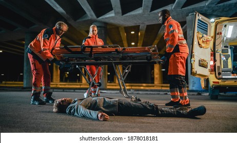 Team Of EMS Paramedics Bring A Stretcher From Ambulance Vehicle And Help An Injured Young Person. Emergency Care Assistants Arrived On The Scene Of A Traffic Accident On A Street At Night.