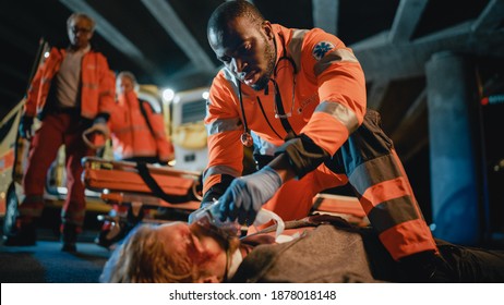 Team of EMS Paramedics Provide Medical Help to an Injured Young Man. Doctor in Gloves Attaches Ventilation Mask on a Patient. Emergency Care Assistants Arrived in an Ambulance Vehicle at Night.