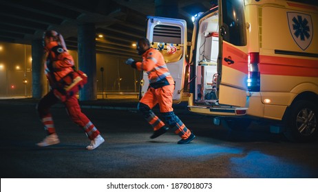 Team of EMS Paramedics Quickly Jump Out from Ambulance Vehicle. Female Doctor Brings First Aid Kit. Emergency Care Assistants Arrived on the Scene of a Traffic Accident on a Street at Night. - Powered by Shutterstock