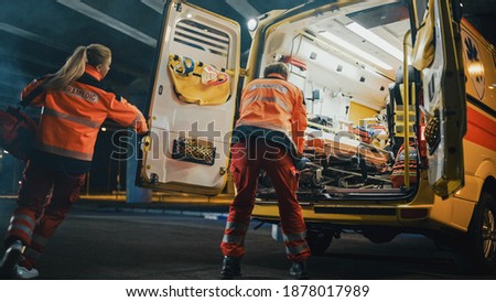 Team of EMS Paramedics Quickly Take Out a Stretcher from Ambulance Vehicle and Help an Injured Person. Emergency Care Assistants Arrived on the Scene of a Traffic Accident on a Street at Night.