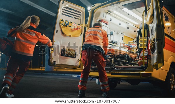 Team of EMS Paramedics Quickly Take Out a\
Stretcher from Ambulance Vehicle and Help an Injured Person.\
Emergency Care Assistants Arrived on the Scene of a Traffic\
Accident on a Street at\
Night.