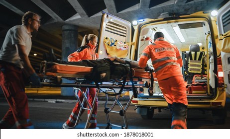 Team of EMS Paramedics React Quick to Provide Medical Help to Injured Patient and Get Him in Ambulance on a Stretcher. Emergency Care Assistants Arrived on the Scene of a Traffic Accident on a Street. Blurry