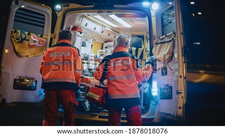 Team of EMS Paramedics React Quick to Provide Medical Help to Injured Patient and Get Him in Ambulance on a Stretcher. Emergency Care Assistants Arrived on the Scene of a Traffic Accident on a Street.